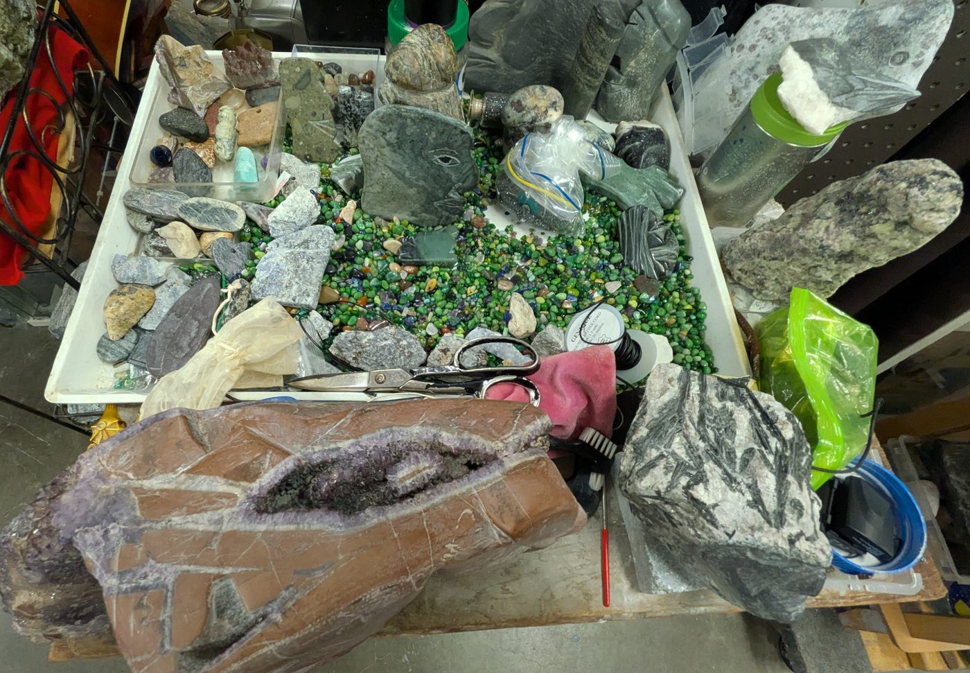 Table d'atelier avec pierres brutes, éclats verts et une géode violette