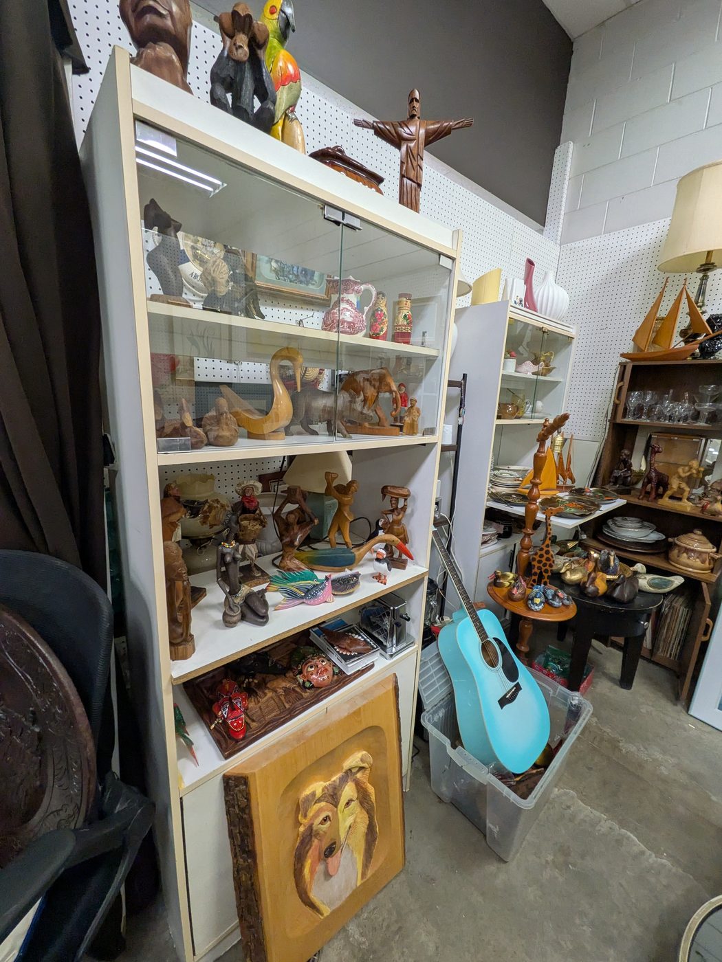 Vitrines blanches remplies de statuettes en bois et de céramiques