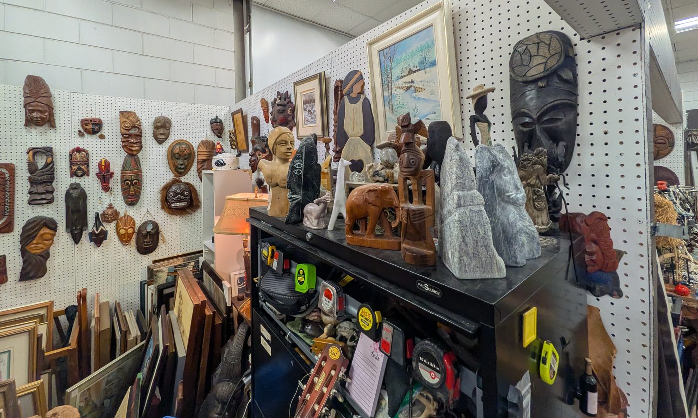 Coin du kiosque avec masques et sculptures sur une tablette noire